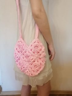 a woman is holding a pink crocheted purse