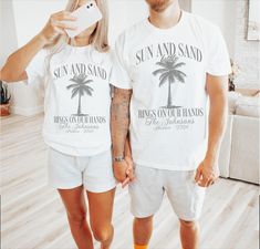 These fun Sun & Sand with Rings on our Hands shirts are the perfect way to celebrate any newly wed couple on their honeymoon! Designed with a fun palm tree they are completely customized and a great way to add some fun to the trip! Simply choose the color and size that you want, then fill out the personalization box with the Couple's name, honeymoon location and the color of ink that you would like for each shirt.   You will receive a customized mockup from me within 24 hours of purchase.  If yo Matching Honeymoon Outfits, White Holiday Shirt For Summer, White Summer Holiday Shirt, Casual Summer Tops For Honeymoon, Destination Wedding Shirts, Just Married Shirts, Wedding Tshirts, Vacation Luxury, Married Shirt