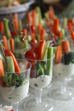 small cups filled with vegetables and dips sitting on top of a white table cloth