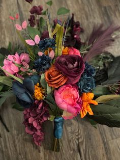 a bouquet of colorful flowers sitting on top of a wooden table