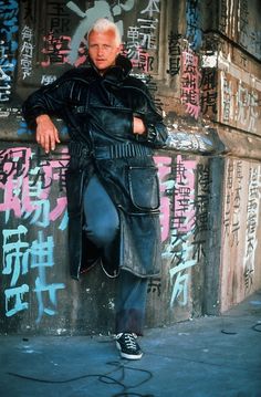 an older man leaning against a wall with graffiti on it's walls behind him