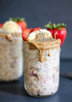 two jars filled with oatmeal and strawberries on top of a table