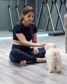 a woman sitting on the floor petting a white dog