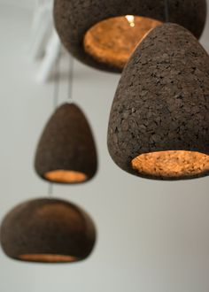 five hanging lights made out of rocks and wood are suspended from the ceiling in an art gallery