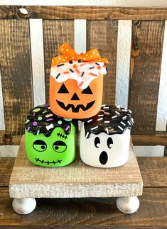 three decorated pumpkins sitting on top of a wooden bench