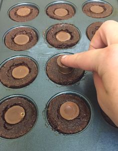 a hand pointing at chocolate cupcakes in a muffin tin