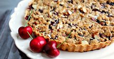 a pie with cherries and almonds on a white plate