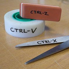 two rolls of tape and scissors on top of a wooden table with the words ctrl - v written on them