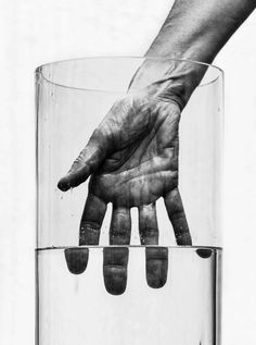 a person's hand reaching into a glass filled with water