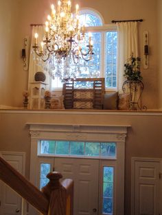 a chandelier hanging from the ceiling in a room with white walls and windows