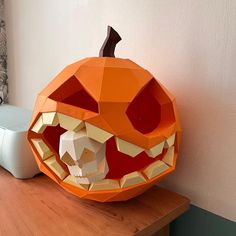 an orange pumpkin with its mouth open on top of a wooden table next to a computer