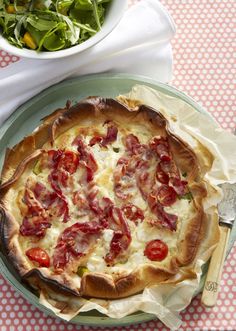 a pizza sitting on top of a table next to a bowl of salad and fork