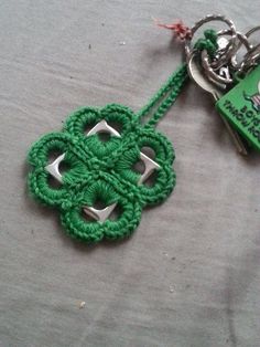 a green keychain with an intricate knot on it's end and a book in the background