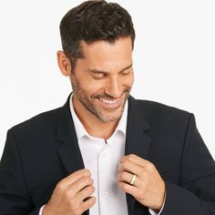 a man in a black suit and white shirt tying his gold ring