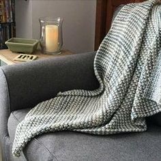 a couch with a blanket on top of it next to a book shelf filled with books