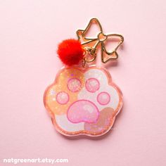 a keychain with a cat's paw print and a red pom - pom