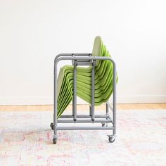 a stack of green chairs sitting on top of a metal rack in front of a white wall