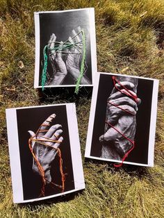 three black and white photographs with colored string wrapped around them on the ground in grass