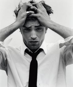 black and white photograph of a young man holding his hands to his head while wearing a tie