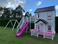 a house with a slide and flowers in the yard