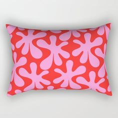 a red and pink rectangular pillow with an abstract design on the front, along with a white background