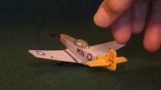 a small toy airplane is being held by a person's hand on the ground