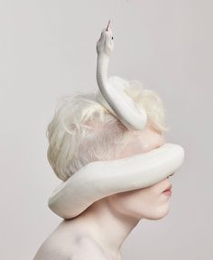 a woman with white hair and a snake on her head