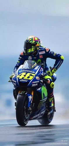 a man riding on the back of a motorcycle down a race track with his hands behind his head