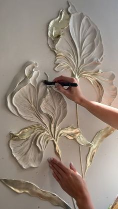 a woman is working on some art work with metal flowers and leaves in the background