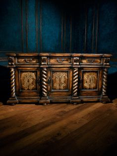 an old wooden cabinet with ornate carvings on the front and sides against a blue wall