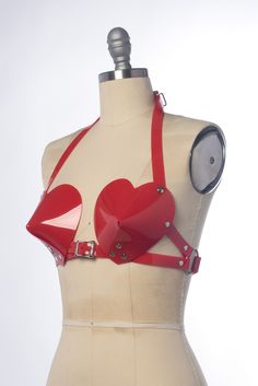 This bullet bra, or "cone bra" is inspired by retro pin-up vixens. This is the-heart-shaped version! Wear alone or layered and add a touch of drama to any outfit. Halter style straps. Buckles in front, back, and behind the neck. Silver-toned nickel plated hardware. Available in PVC, leather, and black vegan leather. Fits up to a DD cup - custom sizing available for larger cup sizes in leather, vegan leather, and clear PVC. Shown in white, clear, and red PVC (both translucent red and the new opaq Bra Art, Vinyl Skirt, Vinyl Skirting, Sticker Inspo, Vinyl Fashion, Leather Fits, Bullet Bra, Rave Bra, Body Adornment