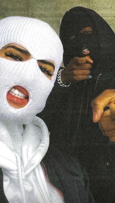 two people wearing white masks and one pointing at the camera while another person puts their finger in his mouth