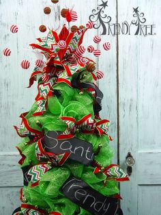 a christmas tree made out of green and red ribbons with a chalkboard sign attached to it