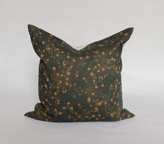 a black and orange pillow with small flowers on the front, sitting on a white surface