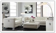 a living room filled with white furniture and large windows in the back drop off wall