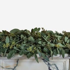 a marble fireplace mantel topped with greenery