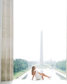 a woman sitting on the ground in front of an obelisk with her legs crossed