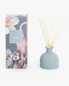 a blue vase next to a box with an animal print on it and a reed diffuser