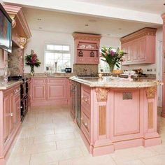 a large kitchen with pink cabinets and marble counter tops on the island in the center