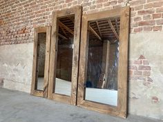 three wooden doors are open in front of a brick wall with exposed rafters on it