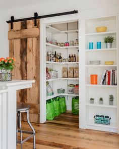 a kitchen with an open pantry door and wooden flooring in the middle of it