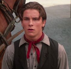 a young man standing next to a horse