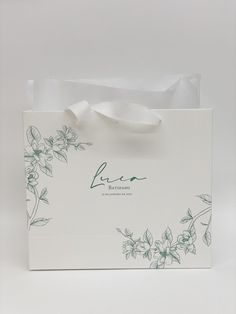 a white paper bag with flowers on the front and green lettering that says love in it