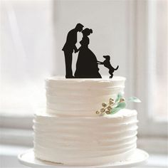 a wedding cake topper with a silhouette of a bride and groom holding a dog