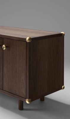 a wooden cabinet with brass handles and knobs on the front, against a gray background