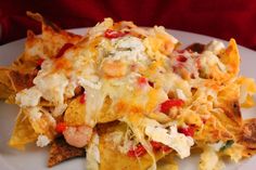 a white plate topped with nachos covered in cheese and toppings on top of tortilla chips