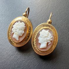 For best prices and offers, please visit our website at https://curiouslytimeless.com/ For sale a very refined pair of cameo earrings that transport you back to the elegance of the early 19th century. These earrings feature two portraits of a man/woman in antique style, which are crafted on shell and on two layers and circled by gold frames with wave motifs. As you wear these earrings, it appears as though the two people is looking at each other. The cameos are mounted in 18K yellow gold and the Gold Oval Cameo Earrings, Gold Cameo Drop Earrings, Victorian Cameo Yellow Gold Earrings, Gold-plated Shell-shaped Earrings, Gold Shell-shaped Shell Earrings, Types Of Shells, Sleeper Earrings, Cameo Earrings, Cameo Jewelry