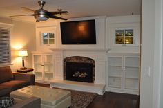 a living room with a couch, fireplace and flat screen tv mounted on the wall