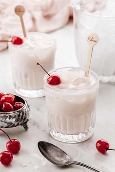 two glasses filled with ice cream and cherries on top of a marble countertop