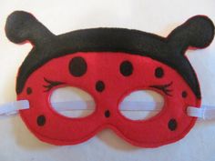 a ladybug mask with black and red dots on the face is laying on a white surface